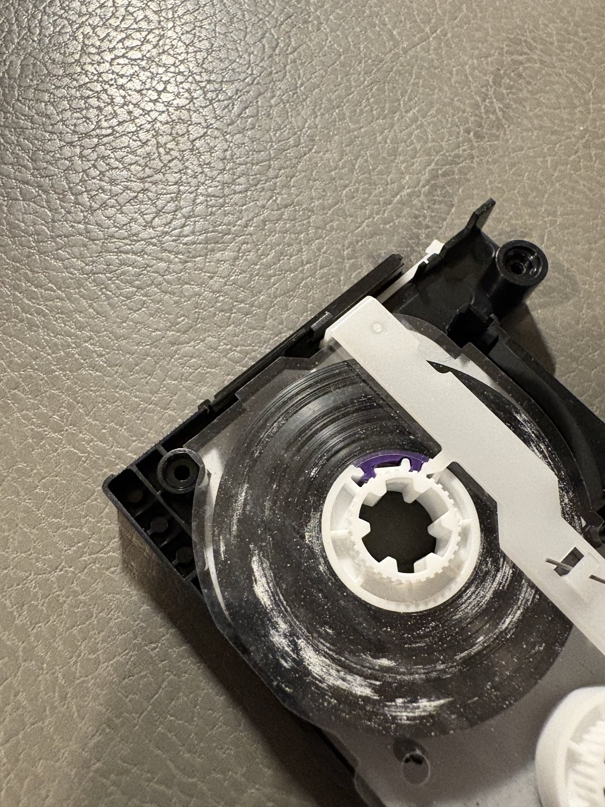 An opened DAT cassette showing residue on the tape pack during condition inspection